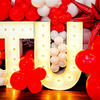 A TU light installation surrounded by cherry and white balloons.